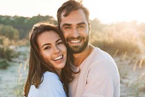 couple smiling at the beach with teeth brightened from cosmetic dentistry meyerland plaza tx