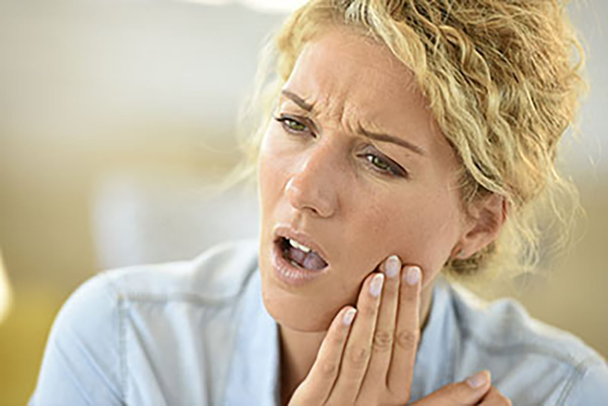 how to prevent tooth decay woman holding her cheek in pain from tooth ache and not learning how to prevent tooth decay for tooth decay prevention