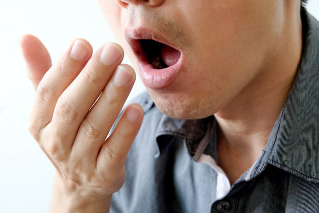 causes of bad breath (2) man checking his breath to see the causes of bad breath