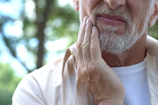 I have a dental emergency senior man holding his jaw in pain thinking I Have a Dental Emergency