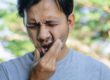 man wincing holding jaw from tooth cavity symptoms
