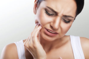 Woman struggles with the pain caused by her impacted teeth